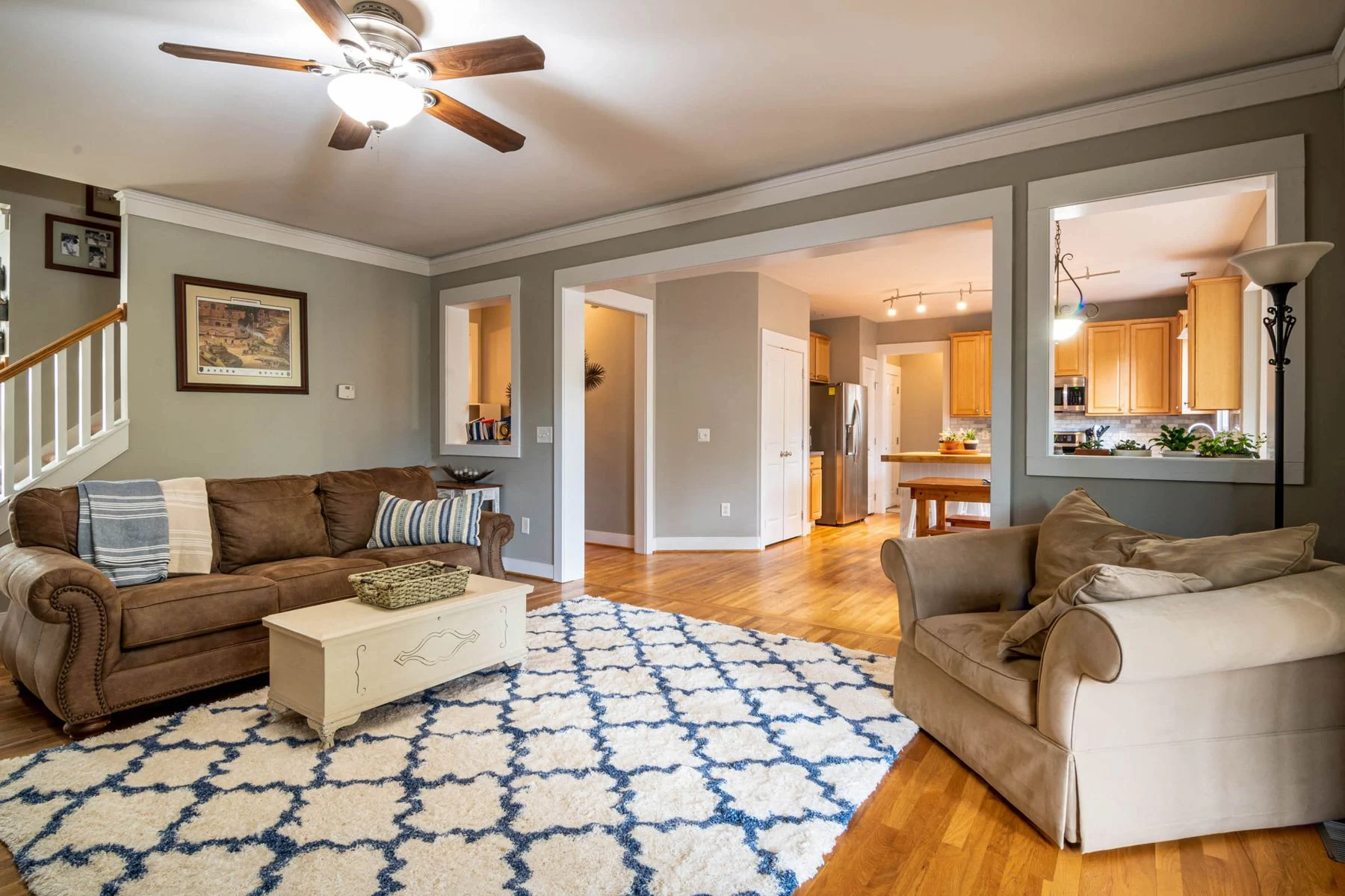 A welcoming everyday living room with comfortable sofas, a patterned rug, and a kitchen beyond