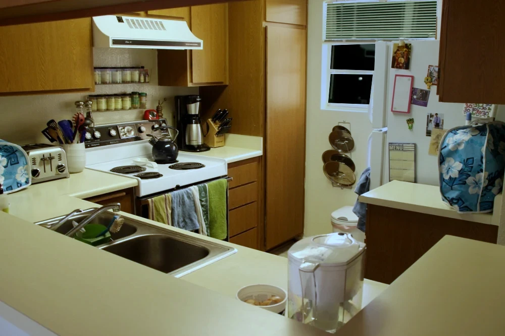 The same home kitchen after cleanup, with cleared counters and evening lighting matched to the before photo